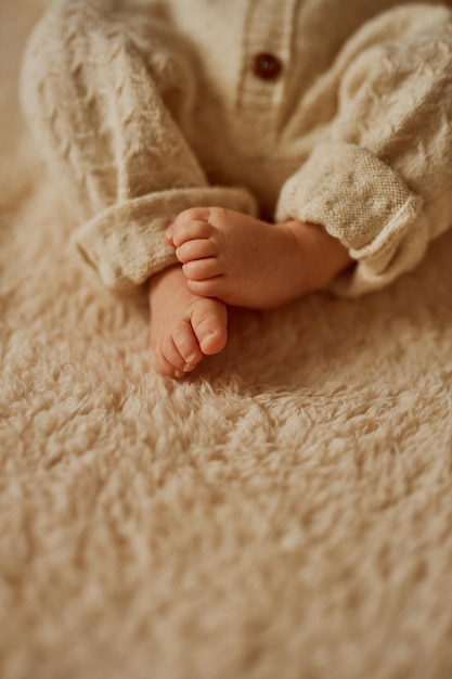 Feet of a newborn the baby is dressed in a warm knitted suit