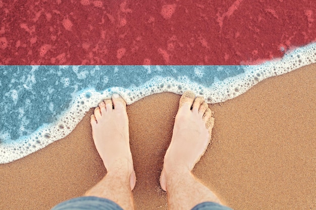 Feet on sandy beach with flag Indonesia Top View on sea surf