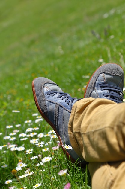 Feet in shoes on green field with flowers