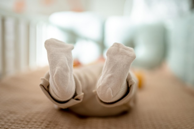 Photo the feet in the socks of a newborn baby lying in the bed