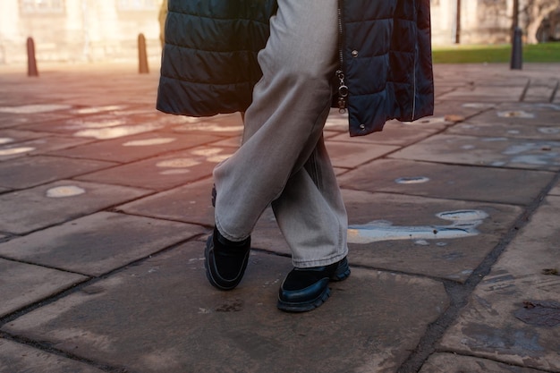 Feet of a woman in a black shoes on the city street on cold day