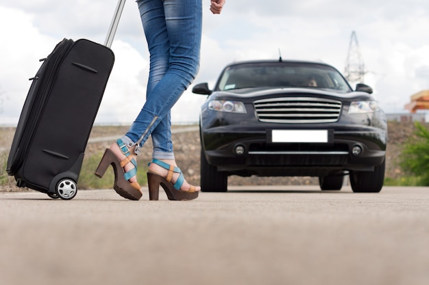 Feet of a woman carrying a black trolley case