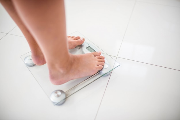 Feet of woman on weighting scale at home