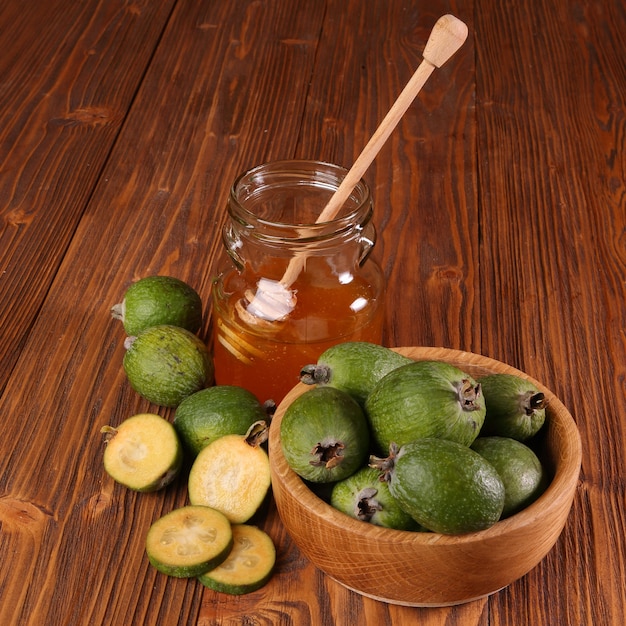 Feijoa Fruits and bank of honey on a wooden table