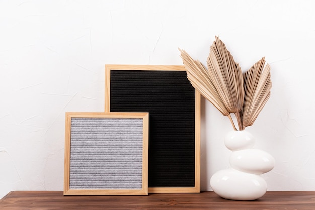 Felt letter boards mockup with dry palm leaves in a vase on wooden table