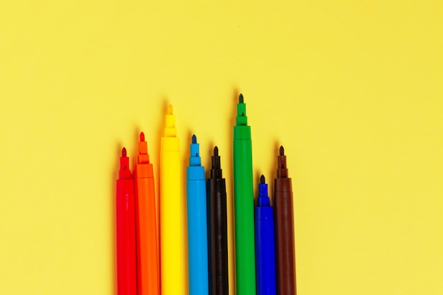 Felttip pens without caps of different colors on a yellow background