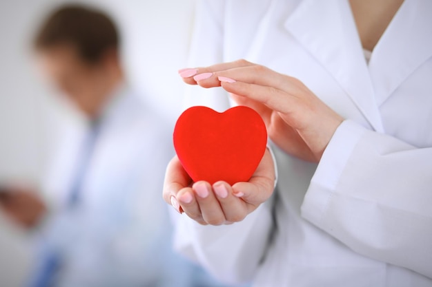 Femail doctor holding a red heart in his hands on a background of the patient