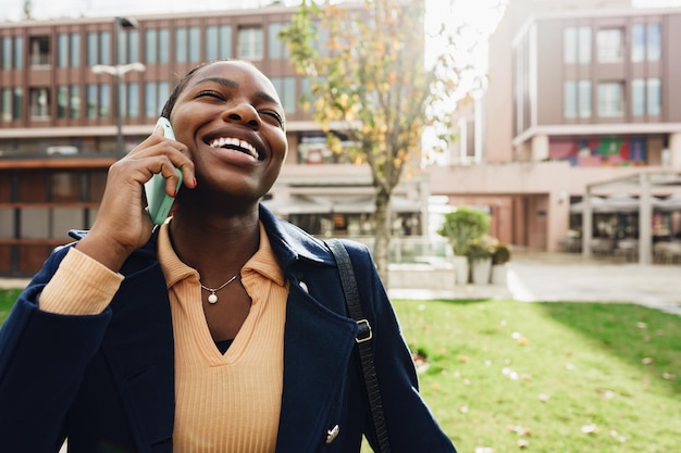 Female african student talking on the phone near the university campus