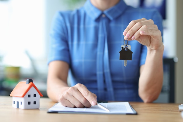 Female agent holds out house keys and pen for signing documents buying real estate concept