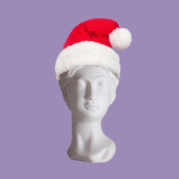 Female antique statue's bust in Santa hat on her head isolated on purple color background