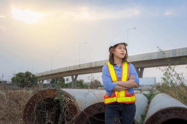 A female architect leader wearing a safety helmet  standing at bridge construction site.