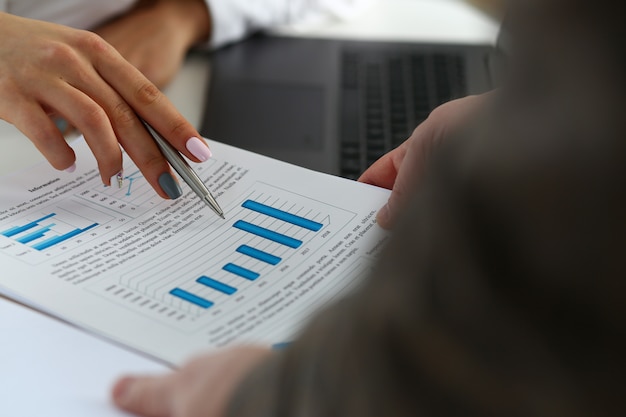 Female arm holding silver pen point in financial graph