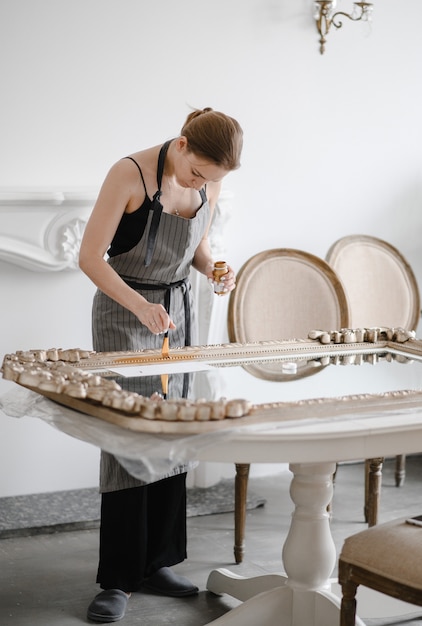 Female artisan hands working on a big wooden picture frame