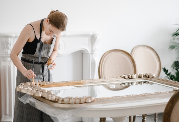 Female artisan hands working on a big wooden picture frame