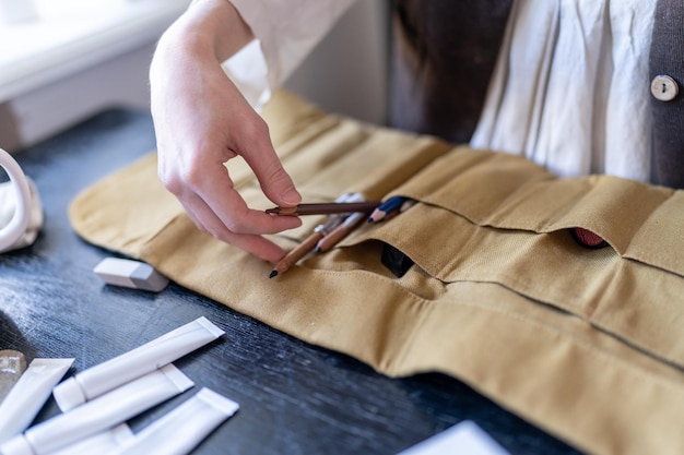 Female artist organizing desk and art supplies in studio