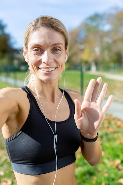 Female athlete after jogging in stadium talking with friends and recording online video blog mature