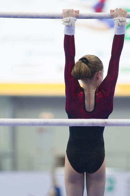 Photo female athlete gymnasts hanging on the bar at the championship