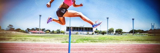 Female athlete jumping above the hurdle