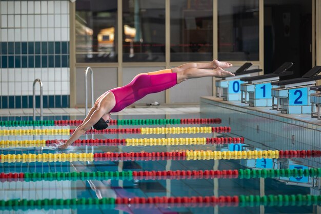 Photo female athlete preparing for a dive start and jumping into the pool