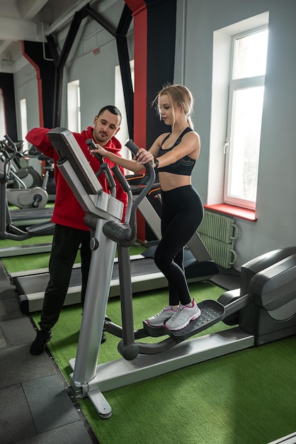 Female athlete with assistant personal trainer running on treadmills People Workout in Fitness Club