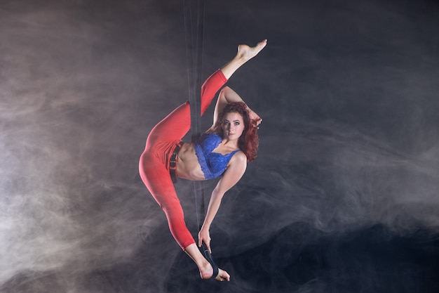 Female athletic sexy flexible aerial circus artist dancing on the silk