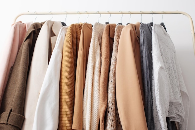 Female autumn clothes on hangers in white room