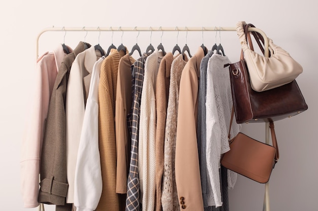 Female autumn clothes on hangers in white room