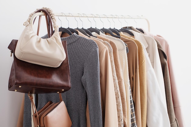 Female autumn clothes on hangers in white room