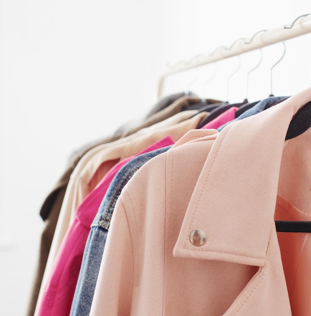 female autumn clothes on hangers in white room