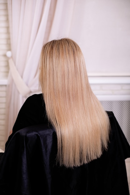 Female back with long, straight, blonde hair, in hairdressing salon