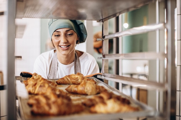 Female baker at the kitchen holding croissant