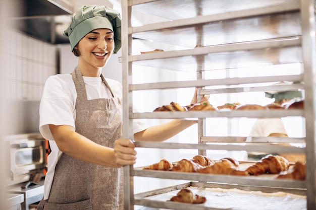 Female baker at the kitchen with croissants