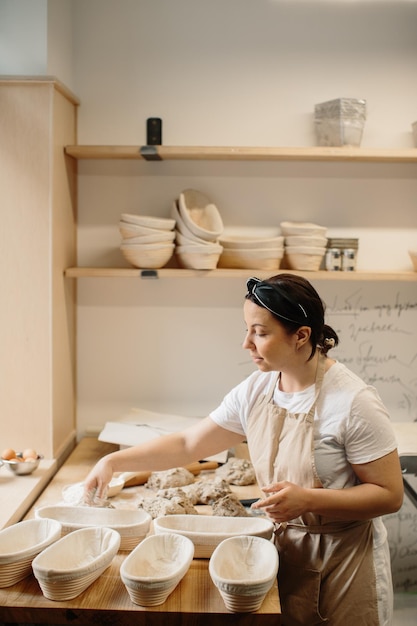 Female baker kneading a dough in bakery shop