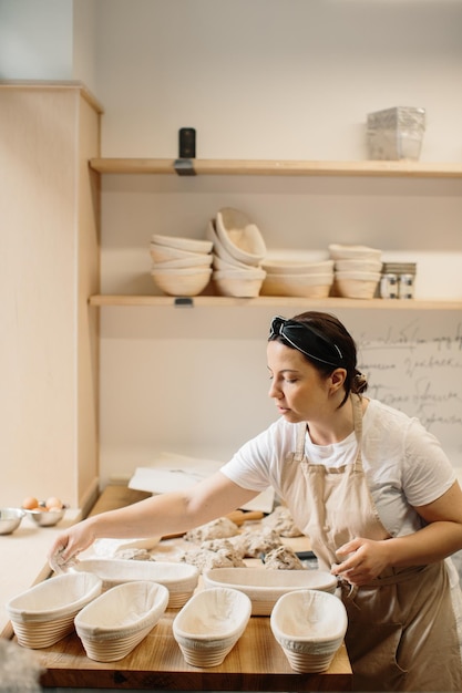 Female baker kneading a dough in bakery shop