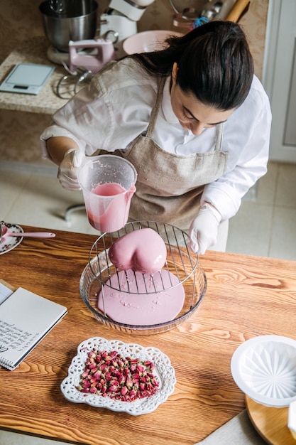 Female baker make perfect custom pink heart shape cake in kitchen bakery online cake store custom