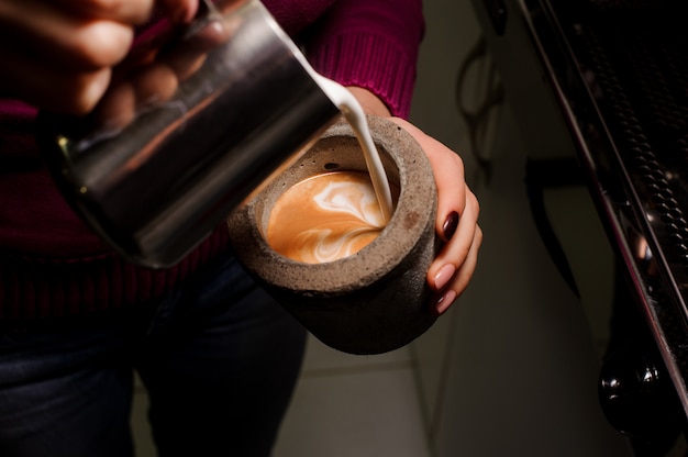 Female barista pouring milk into the concrete pot