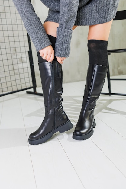 Female beautiful legs in black leather boots and black socks Women's winter shoes