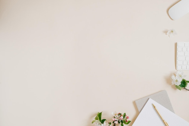 Female blog composition with notebook pen computer and white apple flowers on beige background