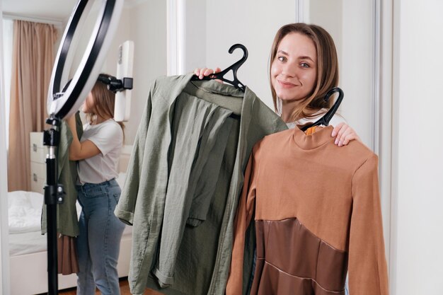 Photo female blogger recording vlog video on smartphone at home online influencer on near wardrobe