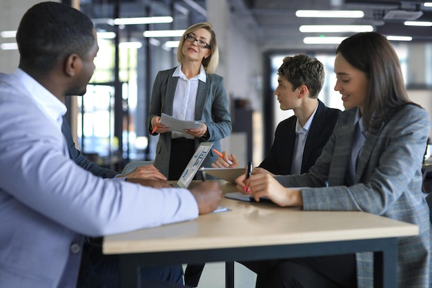 Female boss addressing meeting around boardroom table