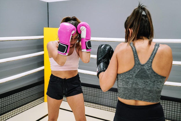 Female boxer in guard position practicing with her partner in the ring