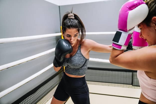 Female boxer throwing a front punch to her opponent in a practice in the ring