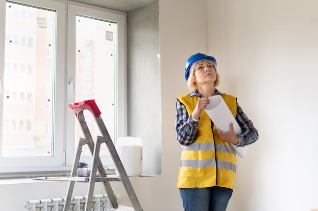 A female Builder looks at the drawings of the object