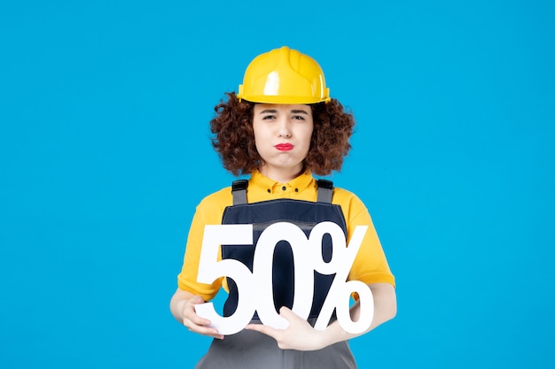 Female builder in uniform with sign on blue