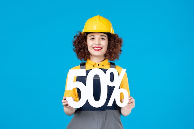 Female builder in uniform with sign on blue