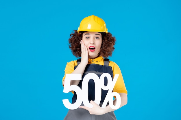 Female builder in uniform with sign on blue