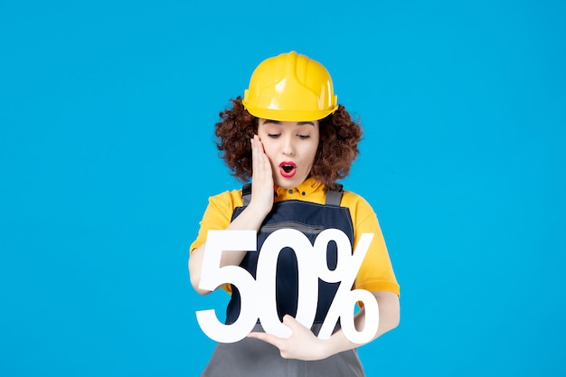 Female builder in uniform with sign on blue