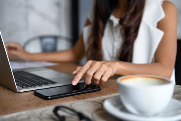 Female businessmen are using smartphone and laptop to work in office.