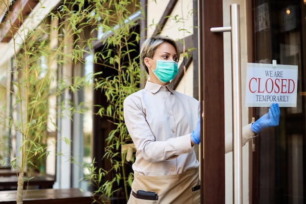 Female cafe owner hanging closed sign due to COVID19 pandemic