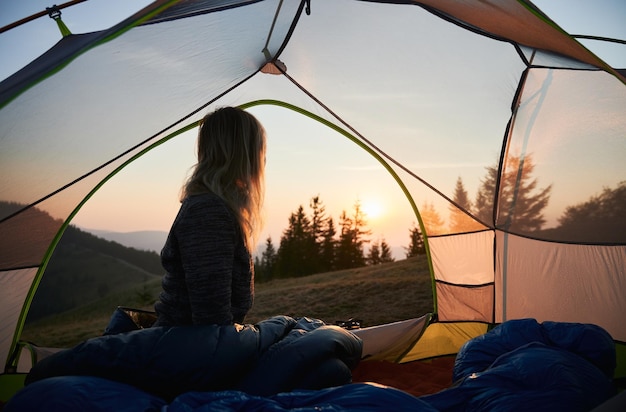 Female camper welcoming cool sunny morning in mountain